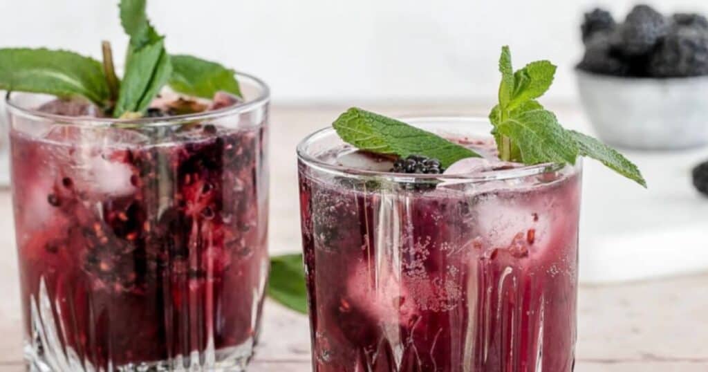 two drinks made with blackberries, decorated with mint leaves