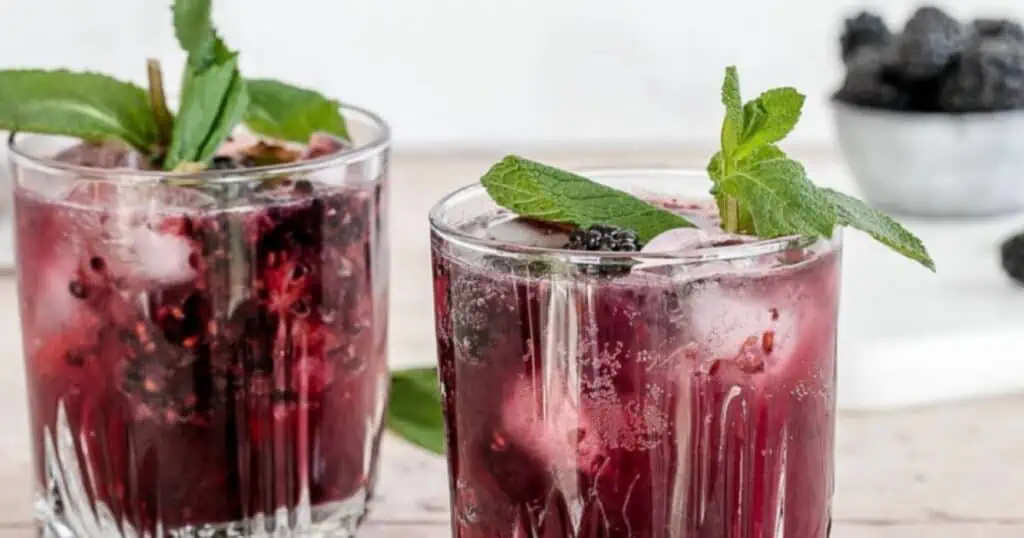 two drinks made with blackberries, decorated with mint leaves