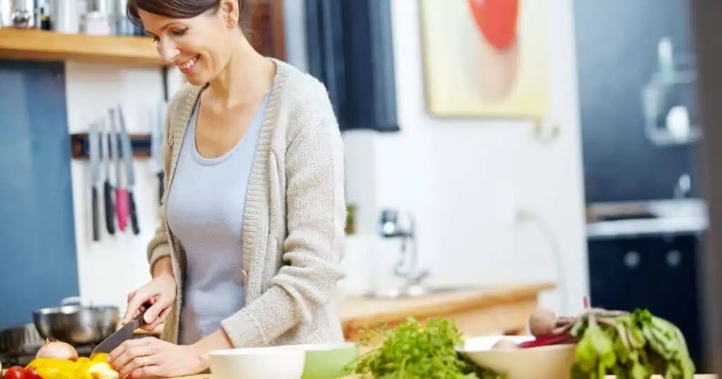 middle aged woman chopping vegetables in kitchen