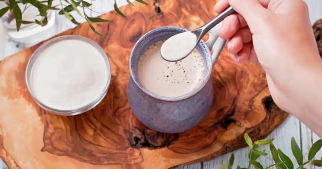 grass fed collagen protein powder being added to coffee in mug with a spoon